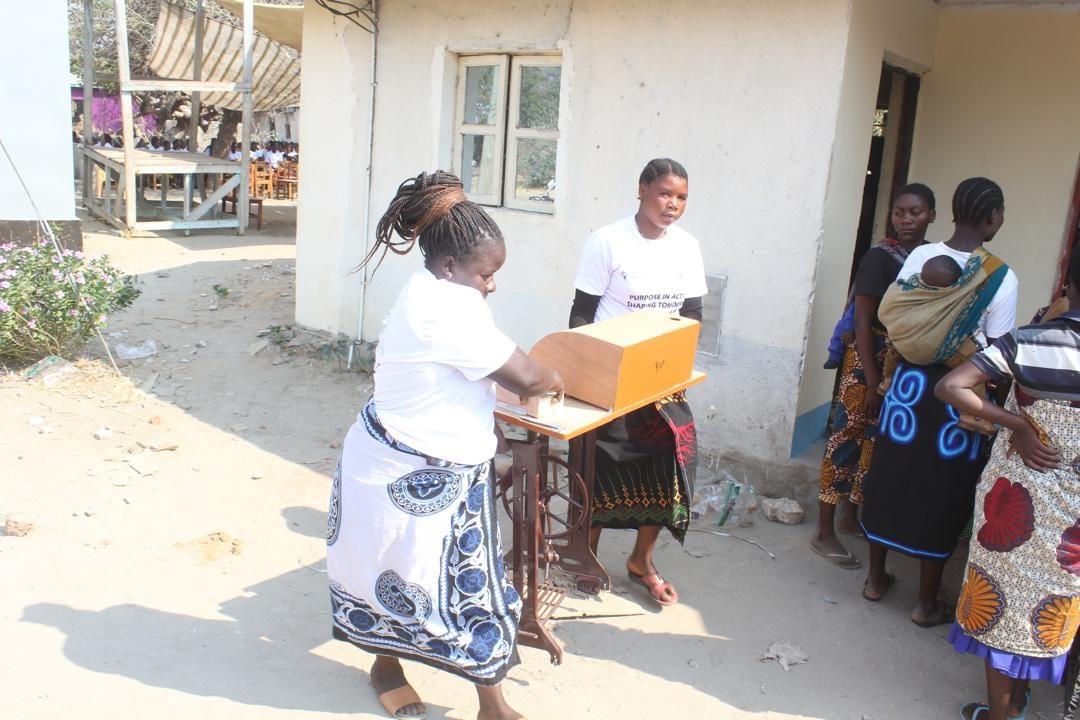 Women carrying a treadle sewing machine into the Ivuna centre
